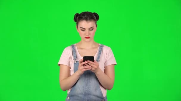 Girl angrily texting on her phone on green screen - Video