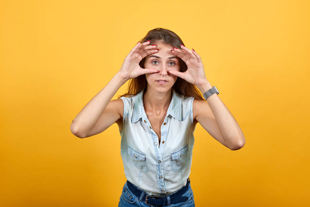 Attractive caucasian young woman doing binoculars gesture - Fotografie, Obrázek