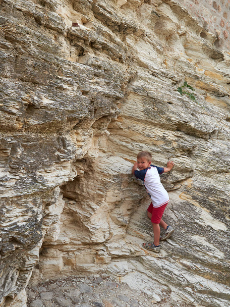 αγόρι σκαρφαλώνει ένα βράχο στο δρόμο της παλιάς πόλης Arkua Petrarka, Ιταλία - Φωτογραφία, εικόνα