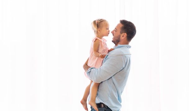 Дочка цілує свого батька, сидячи на руках
 - Фото, зображення