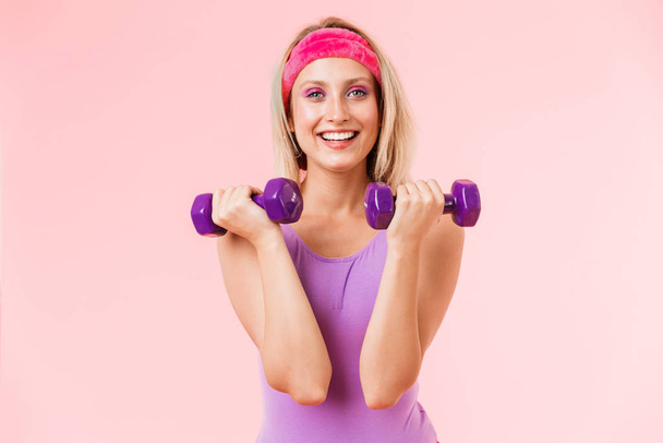 Image of happy attractive woman holding dumbbells and smiling - Zdjęcie, obraz