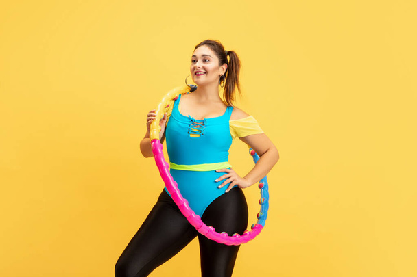 Young caucasian plus size female models training on yellow background - Fotoğraf, Görsel