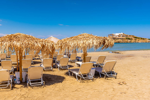 Lettini con ombrelloni sulla spiaggia di Agios Georgios, località molto popolare sull'isola di Naxos, Grecia
. - Foto, immagini