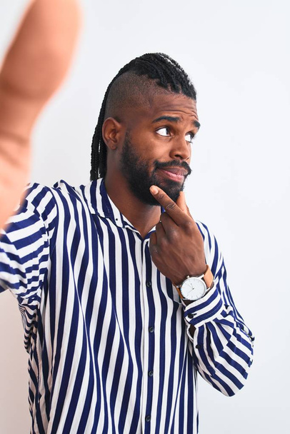 African american man with braids make selfie by camera over isolated white background serious face thinking about question, very confused idea - Foto, Imagen