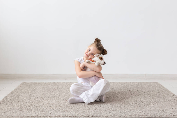Pet, childhood and animal concept - Portrait of little child girl sitting on the floor with puppy Jack Russell Terrier - Fotoğraf, Görsel