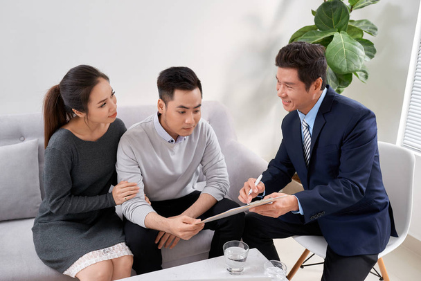 Sales Consultant showing new investment plans to young asian couple - Photo, Image