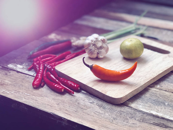 zblízka chilli papriček, česneku a vápna na dřevěné řezací desce - Fotografie, Obrázek