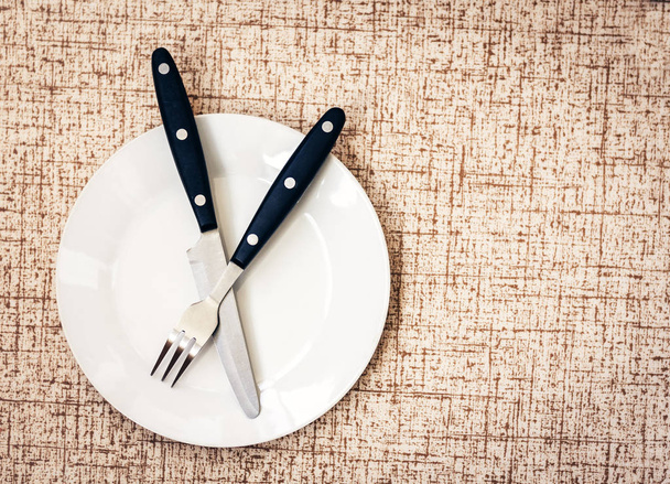 White empty plate with knife and fork crossed on wooden backgrou - Foto, Imagen