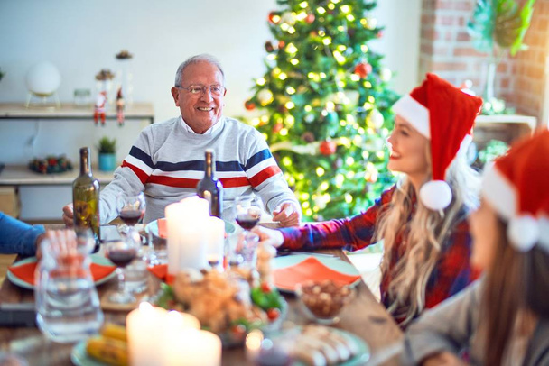 Piękna rodzina w kapeluszu Świętego Mikołaja, uśmiechnięta szczęśliwa i pewna siebie. Jedzenie pieczonego indyka świętującego Boże Narodzenie w domu - Zdjęcie, obraz