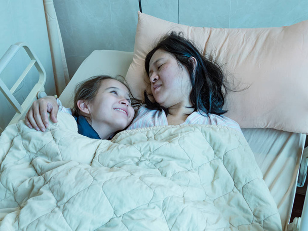 Madre e hija acostadas juntas en la cama de hosital
 - Foto, imagen