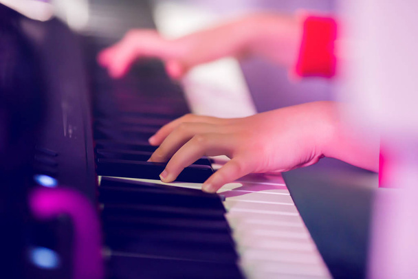 De hand van een close-up kind die piano speelt op het podium met verlichting. Favoriet - Foto, afbeelding