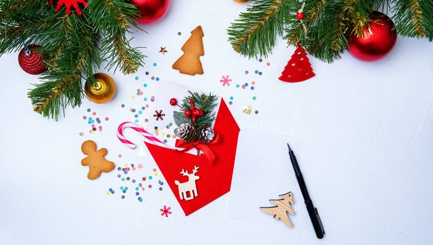 Фото червоного конверта, печива, гілок ялини Різдвяні прикраси на білому тлі
 - Фото, зображення