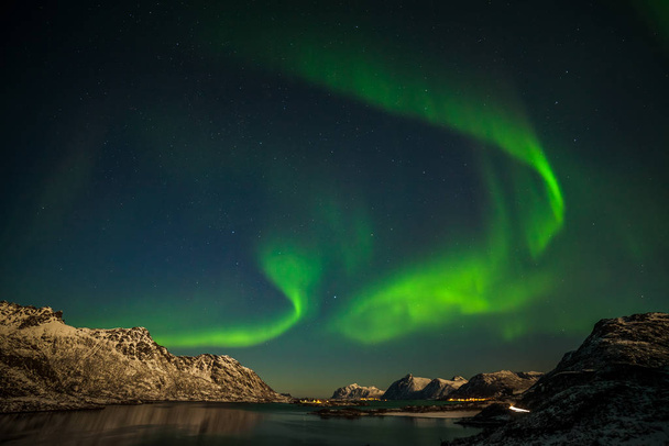 北ヨーロッパの山々の上の劇的なオーロラ、極の光-ロフトテン島、ノルウェー - 写真・画像