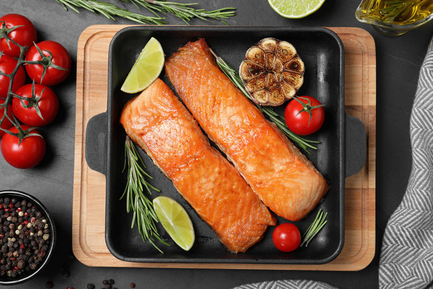 Delicious roasted fish served on black table, flat lay - Photo, image