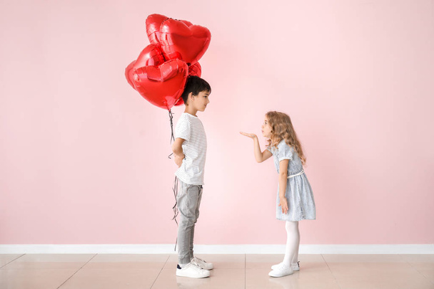Little girl sending kiss for cute boy with air balloons on color background. Valentines Day celebration - Foto, immagini