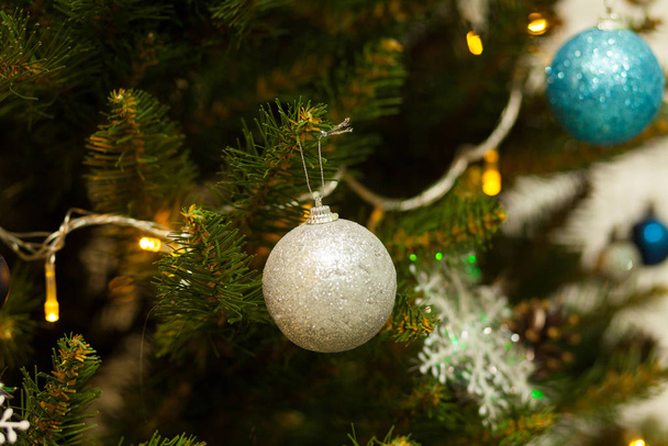 Beautiful green Christmas tree decorated with balls and garlands. Close-up photo - Foto, afbeelding