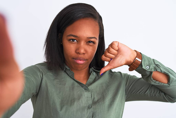 Beautiful young african american woman taking selfie over isolated background with angry face, negative sign showing dislike with thumbs down, rejection concept - Fotó, kép