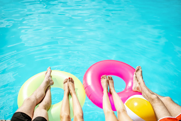 Pernas nos anéis infláveis na piscina
 - Foto, Imagem