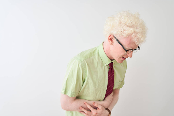 Молодой бизнесмен-альбинос в рубашке и галстуке стоит на изолированном белом фоне с рукой на животе, потому что тошнота, болезненное заболевание чувствует себя нездоровым. Концепция Ache
. - Фото, изображение