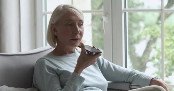 Older woman holding phone using virtual digital voice recognition - Video, Çekim
