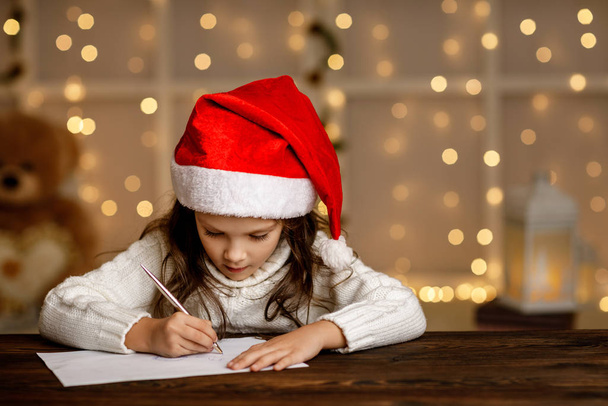 child girl in santa hat writing letter to Santa Claus - Photo, Image