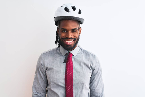 Afrykański amerykański biznesmen z warkoczami noszący kask rowerowy na białym tle ze szczęśliwym i chłodnym uśmiechem na twarzy. Szczęśliwy człowiek.. - Zdjęcie, obraz
