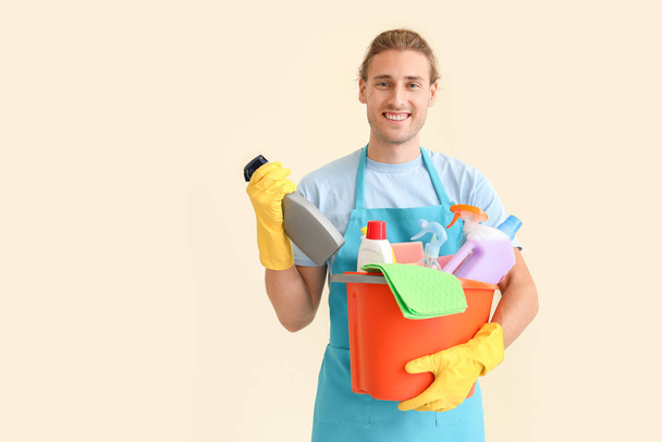 Homem zelador com suprimentos de limpeza em fundo claro
 - Foto, Imagem