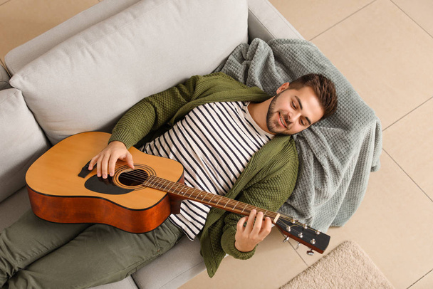 Handsome young man playing guitar at home - Foto, Imagem
