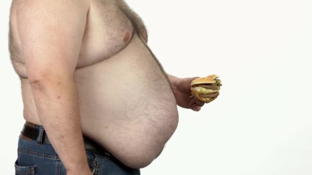 Tlustý muž jíst fast food hamburger. - Záběry, video