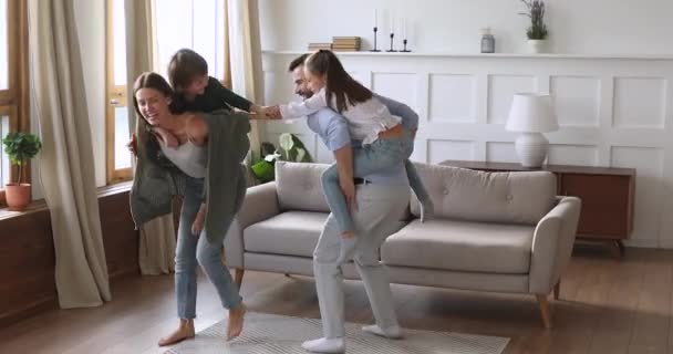 Funny happy parents carrying kids playing game in living room - Filmagem, Vídeo