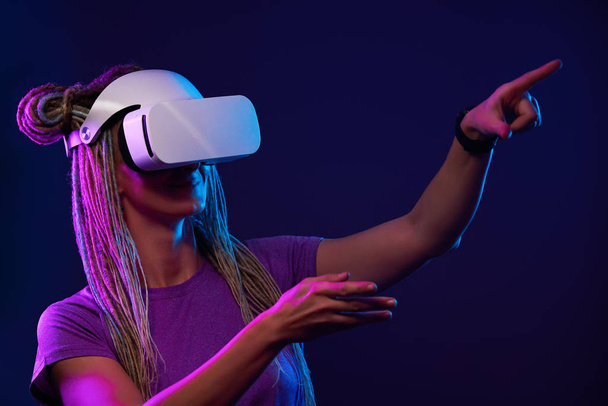 La mujer está usando auriculares de realidad virtual. Retrato de estudio de luz de neón. - Foto, Imagen