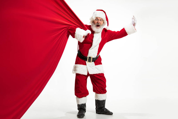 Santa Claus pulling huge bag full of christmas presents isolated on white background - 写真・画像