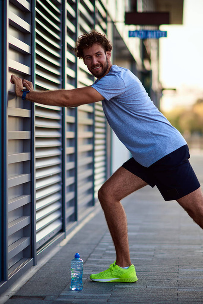 Спортсмен розтягується в міській зоні під час бігу / вправ
. - Фото, зображення