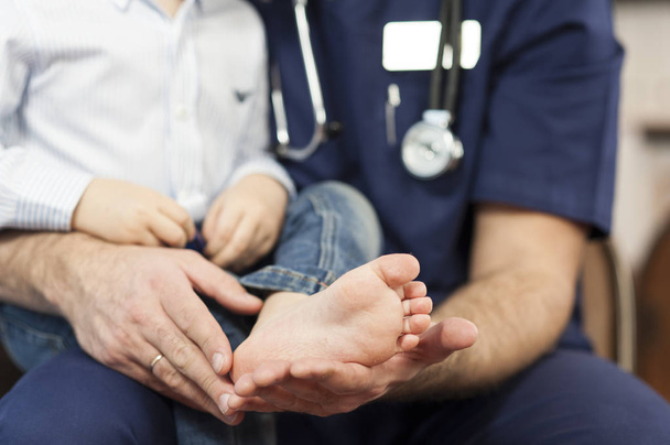 Der Kinderarzt untersucht die Füße des Kindes, der Hautarzt behandelt die Fersen-, Fuß- und Fersenmassagen. - Foto, Bild