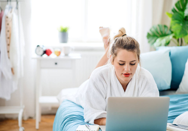 Young woman with laptop on bed indoors at home in the morning. - Foto, Imagen