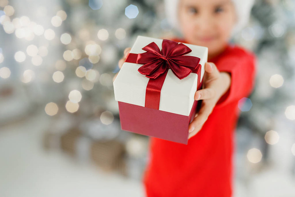Adorable Child holding Christmas  paper wrapped present in hands  - Fotografie, Obrázek