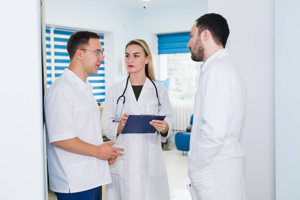 visão de alto ângulo de três médicos em casacos brancos conversando na sala do hospital
 - Foto, Imagem