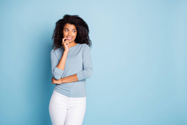 Photo of cheerful cute nice pretty girl biting nails looking into empty space planning her cunning idea in white pants trousers isolated pastel color background - Zdjęcie, obraz