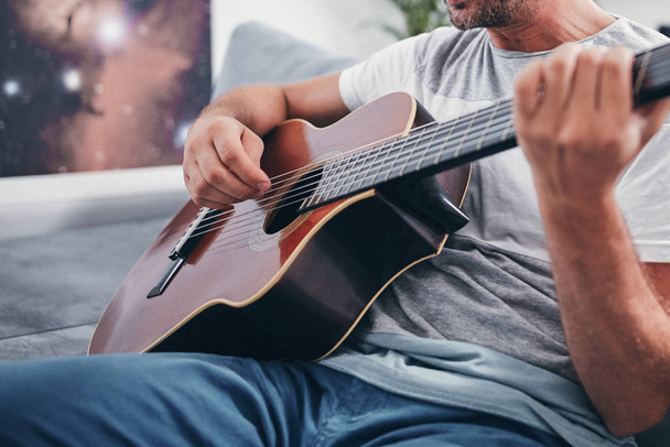 Człowiek gra na gitarze akustycznej w salonie. - Zdjęcie, obraz