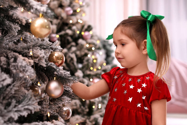 Cute little child near Christmas tree at home - Foto, Imagen