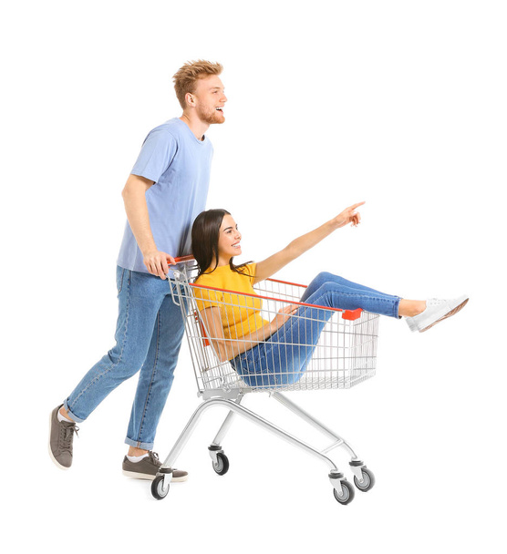 Young couple with shopping cart on white background - Foto, immagini