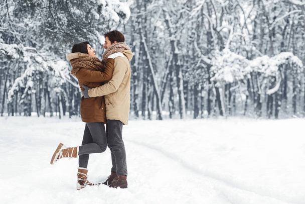 Пара обнимающихся, стоящих в снежном зимнем лесу утром
 - Фото, изображение