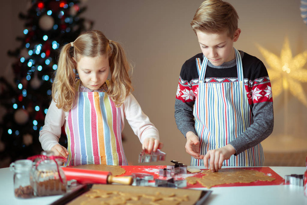 Happy siblings children preparing Christmas cookies at home with - Zdjęcie, obraz
