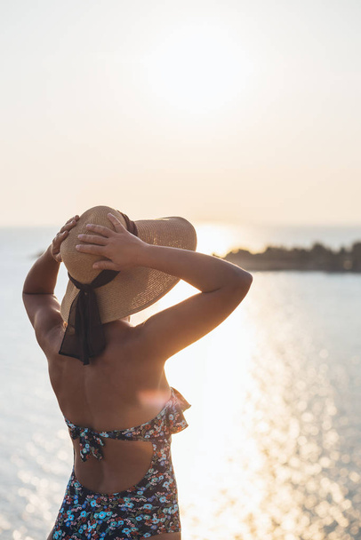 Jovem desfrutando ao pôr do sol no penhasco à beira-mar
 - Foto, Imagem