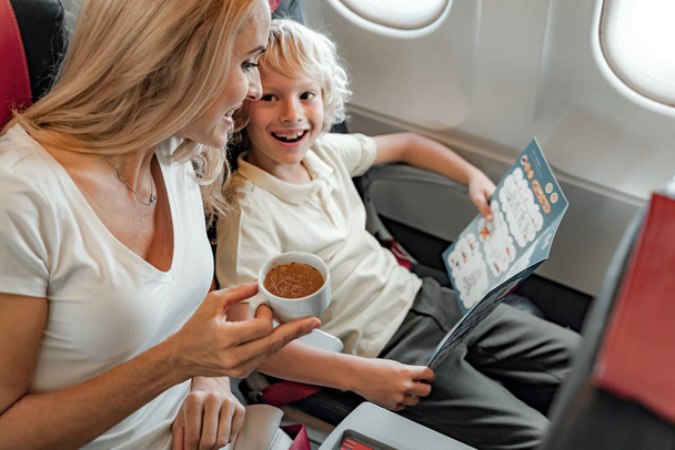 Smiling woman is enjoyioing coffee in plane - Фото, изображение