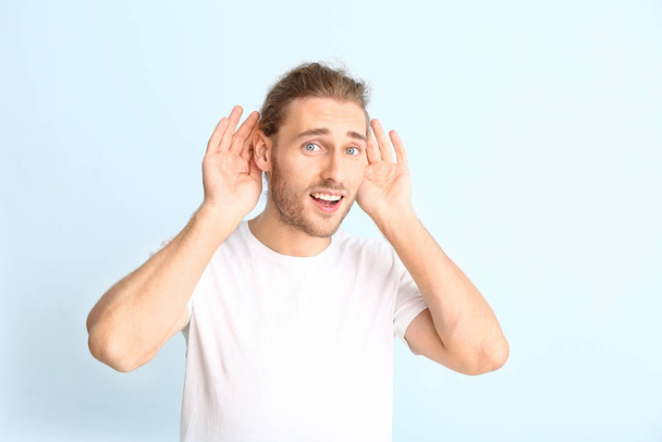Young man with hearing problem on light background - Foto, imagen