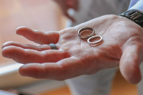 A high angle selective focus shot of a person holding wedding rings - Valokuva, kuva
