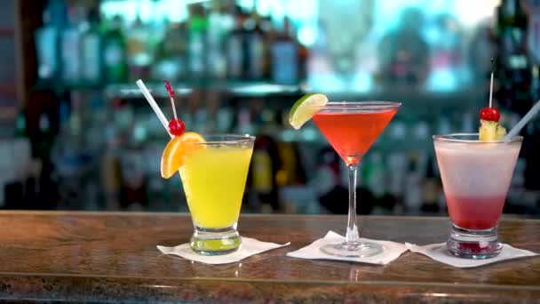 Três copos com bebidas alcoólicas coloridas no balcão do bar, close-up de coquetéis
 - Filmagem, Vídeo