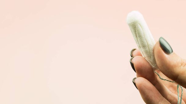 Primer plano de la mano de la mujer sosteniendo la menstruación tampón de algodón
 - Foto, Imagen