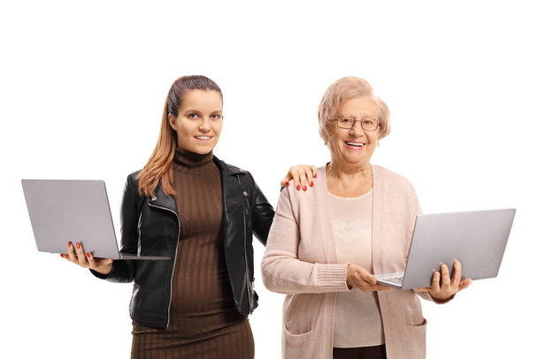 Granddaughter and grandmother holding laptop computers - 写真・画像
